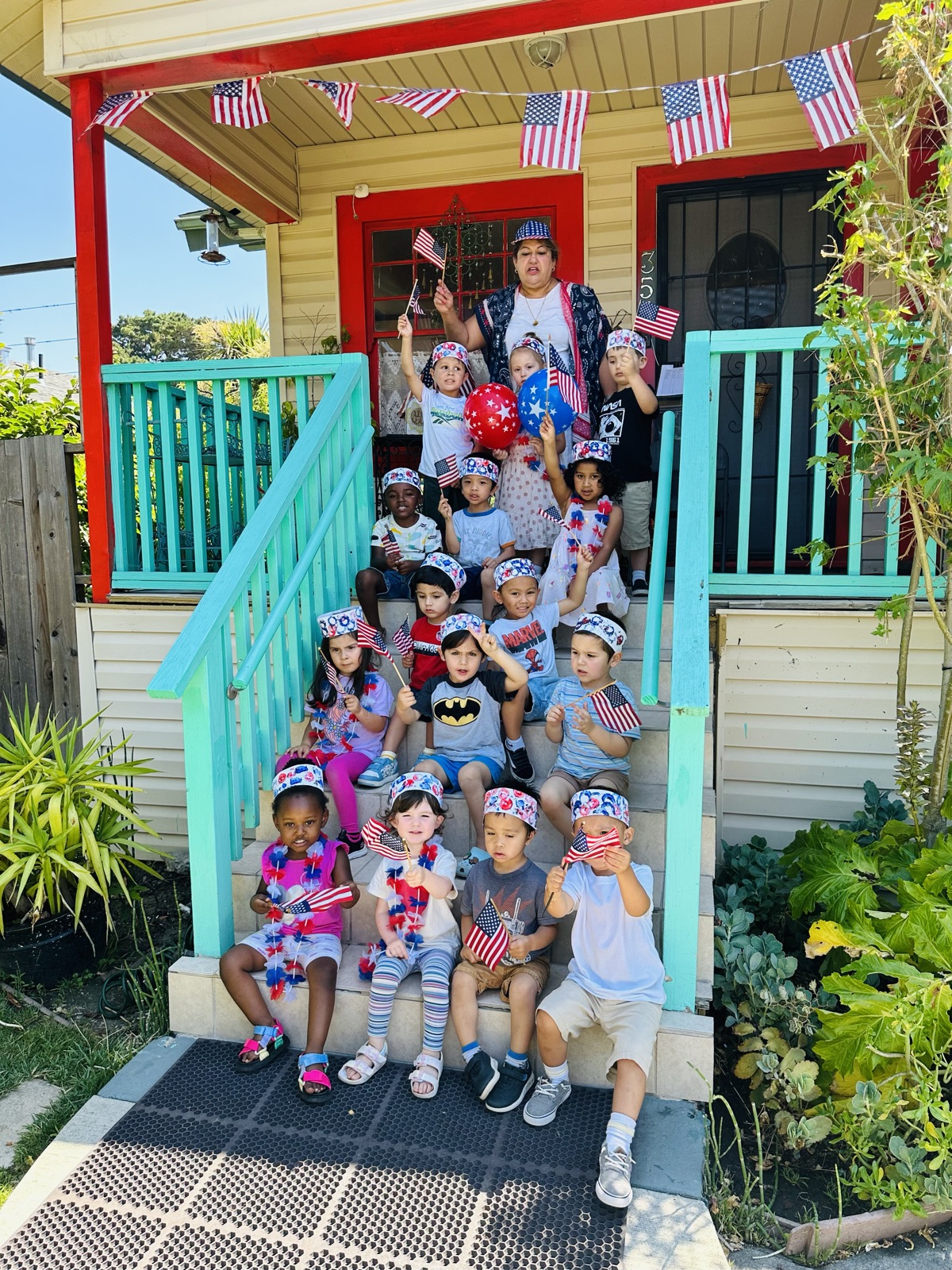 The whole class waves flags on the school's decorated porch steps