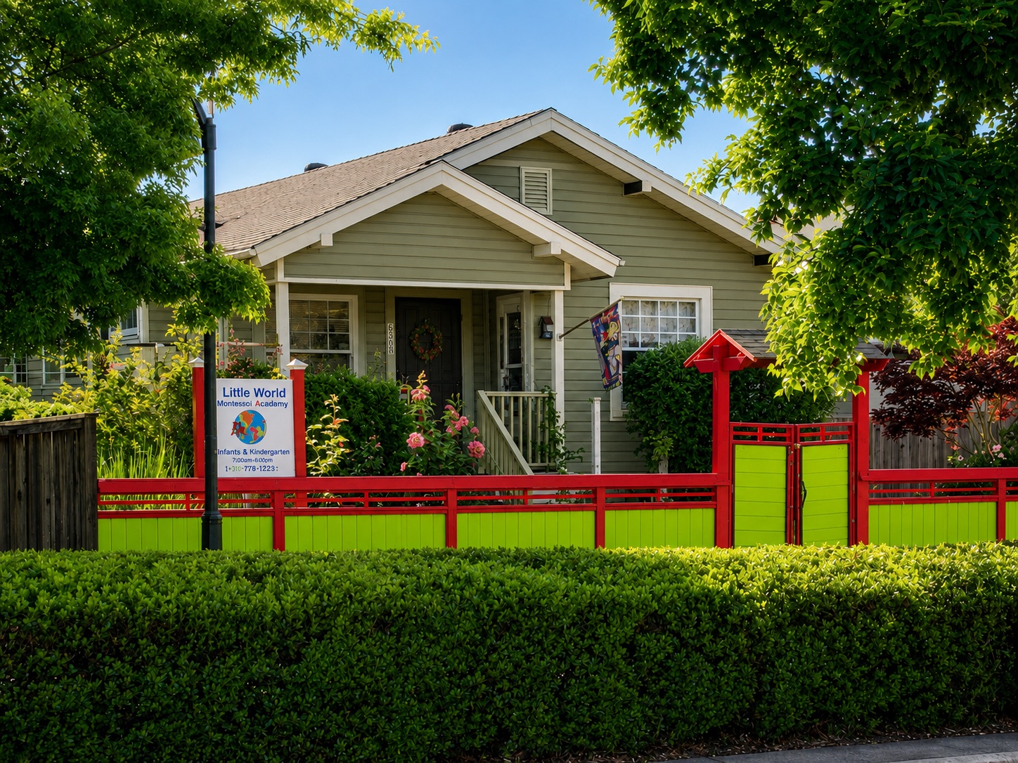 The front of A Little World Montessori behind its cheerful, brightly painted fence, framed by leafy trees