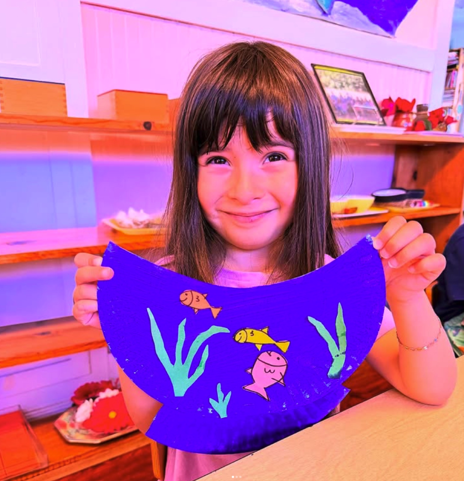 A student proudly presents her paper-plate aquarium